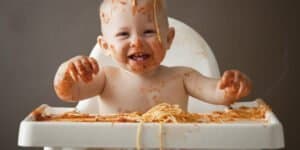 image of baby covered in spaghetti Bolognese, laughing and sitting in a high-chair for the article You cant implement a CRM database with dirty data or can you?