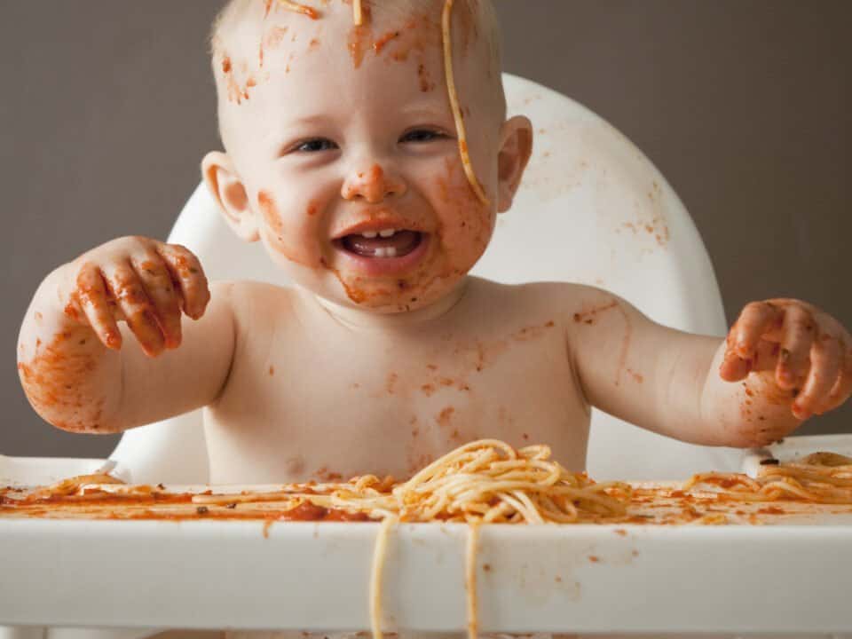 image of baby covered in spaghetti Bolognese, laughing and sitting in a high-chair for the article You cant implement a CRM database with dirty data or can you?