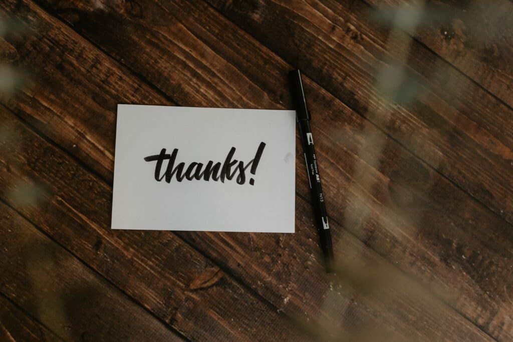 thanks note and a pen on a wooden surface for keep your emails simple and effective