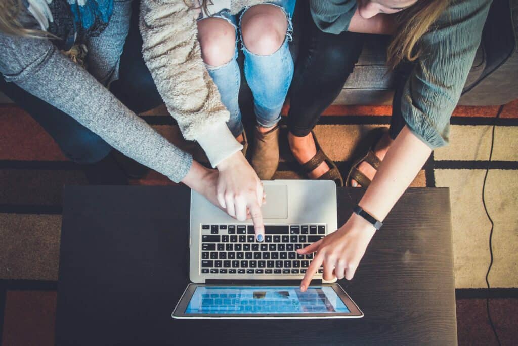 topdown image of three people pointing at laptop screen representing customer retention