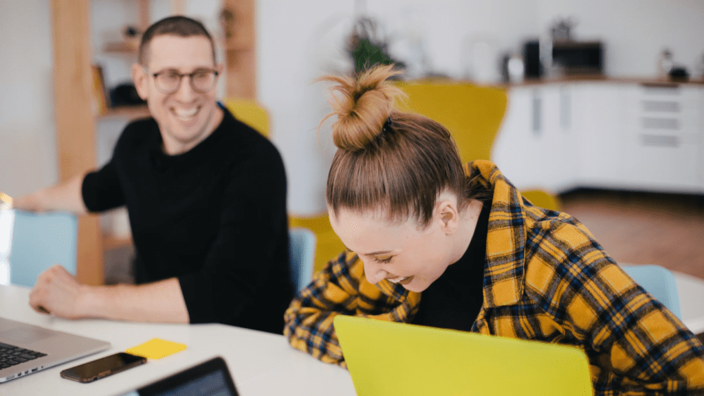 two persons with laptops in front of them look happy and smiling image for prospect relationship management article