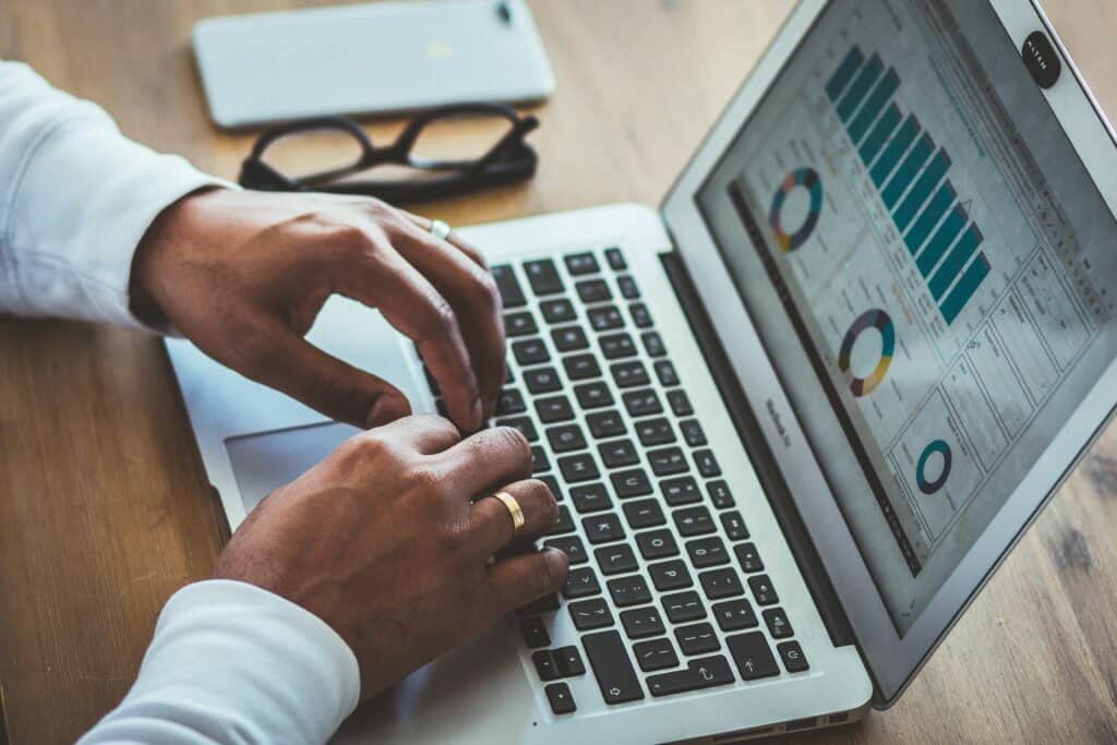 closeup view of person looking at statistics on macbook for successful sales behaviours article