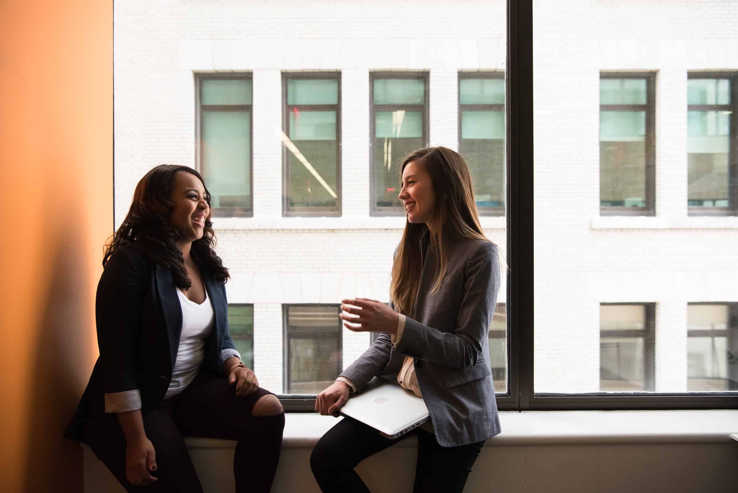 two women sitting by the window having a conversation for best salesman/salesperson article