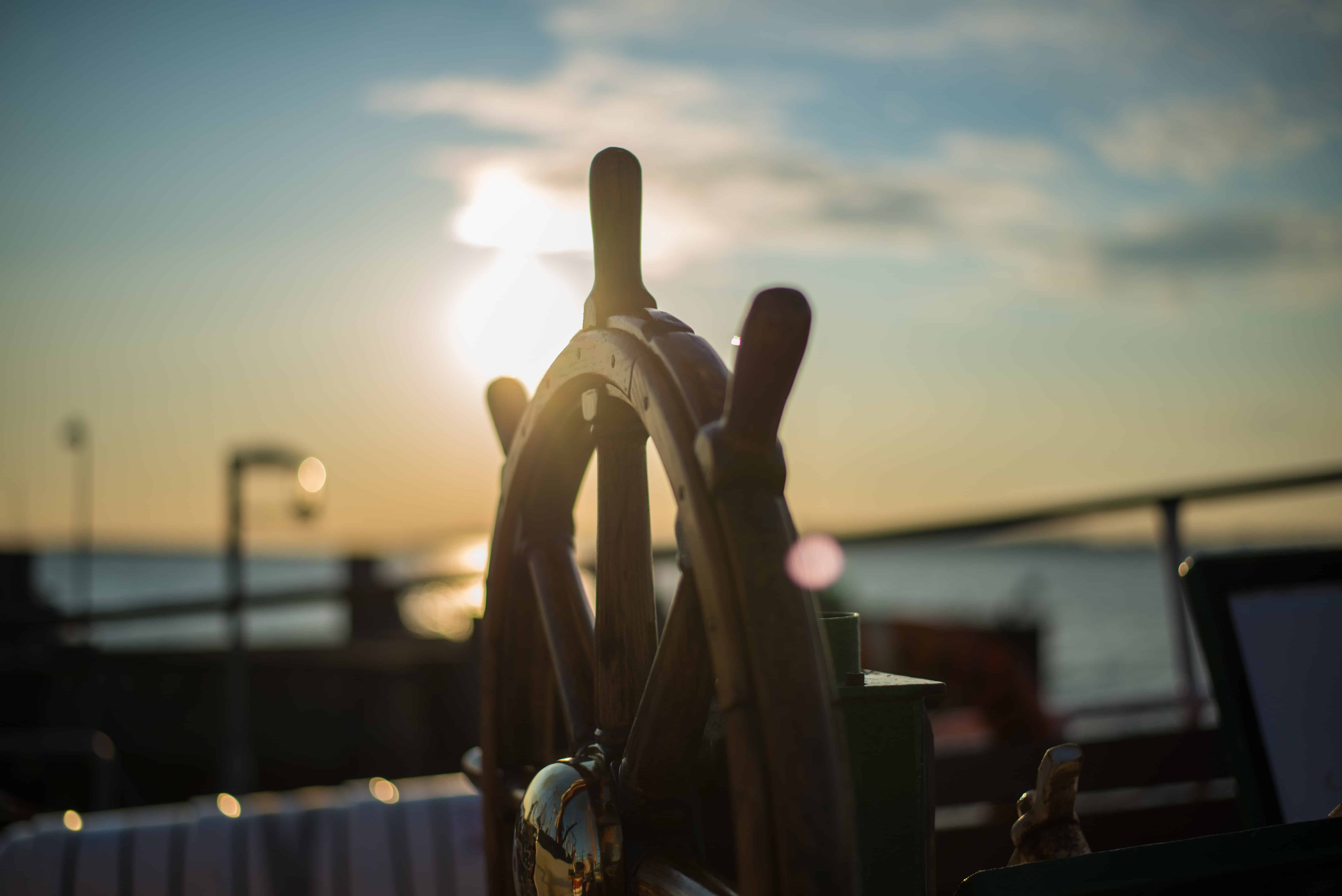 ship wheel on boat with setting sun behind for crms improve productivity article