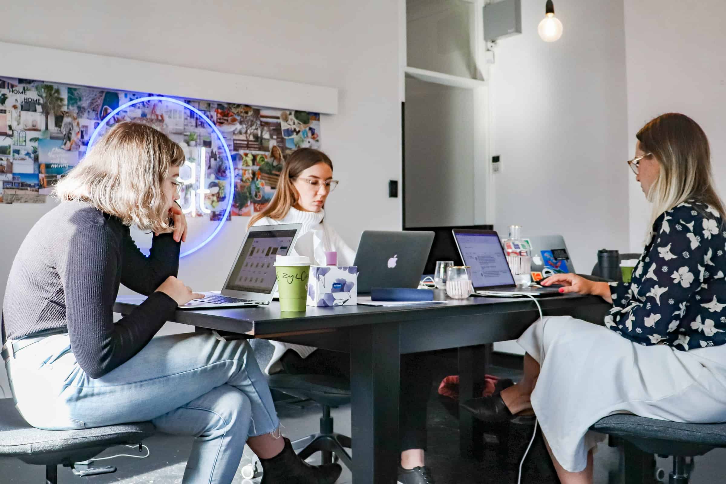 3 women sitting in front of a desk working on laptops for visualising sales process for sales conversion rate article