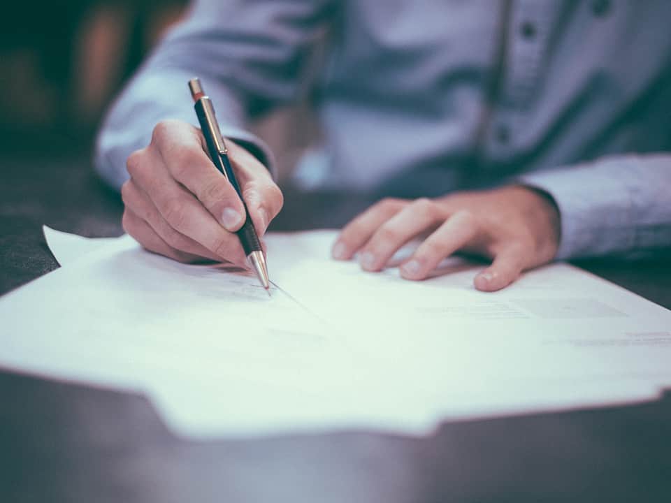 man writing on multiple sheets of papers for prospect list multiple spreadsheets