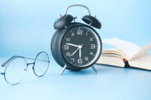 thin-rimmed glasses, an alarm clock and a book with sky blue background for never forgetting a followup article