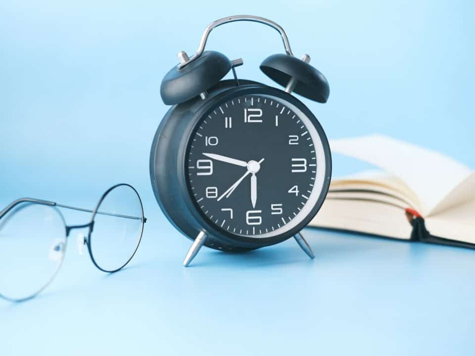 thin-rimmed glasses, an alarm clock and a book with sky blue background for never forgetting a followup article