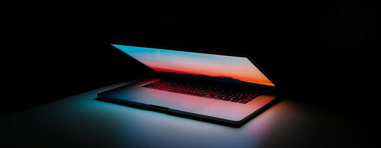 black laptop with blue and red screen glowing against black background for simple crm article