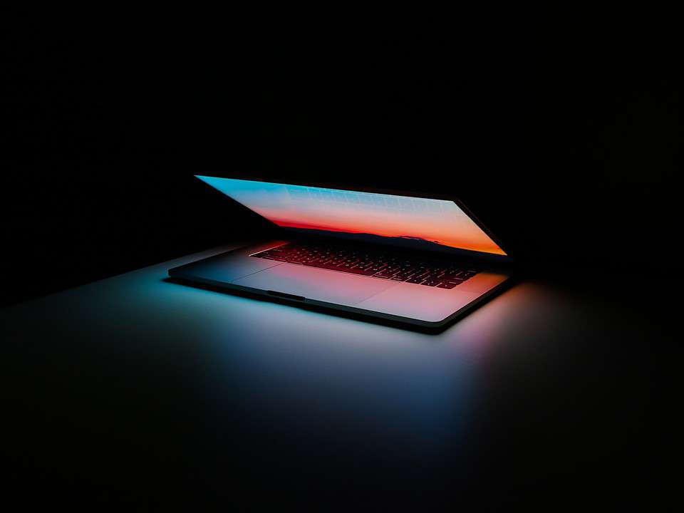 black laptop with blue and red screen glowing against black background for simple crm article