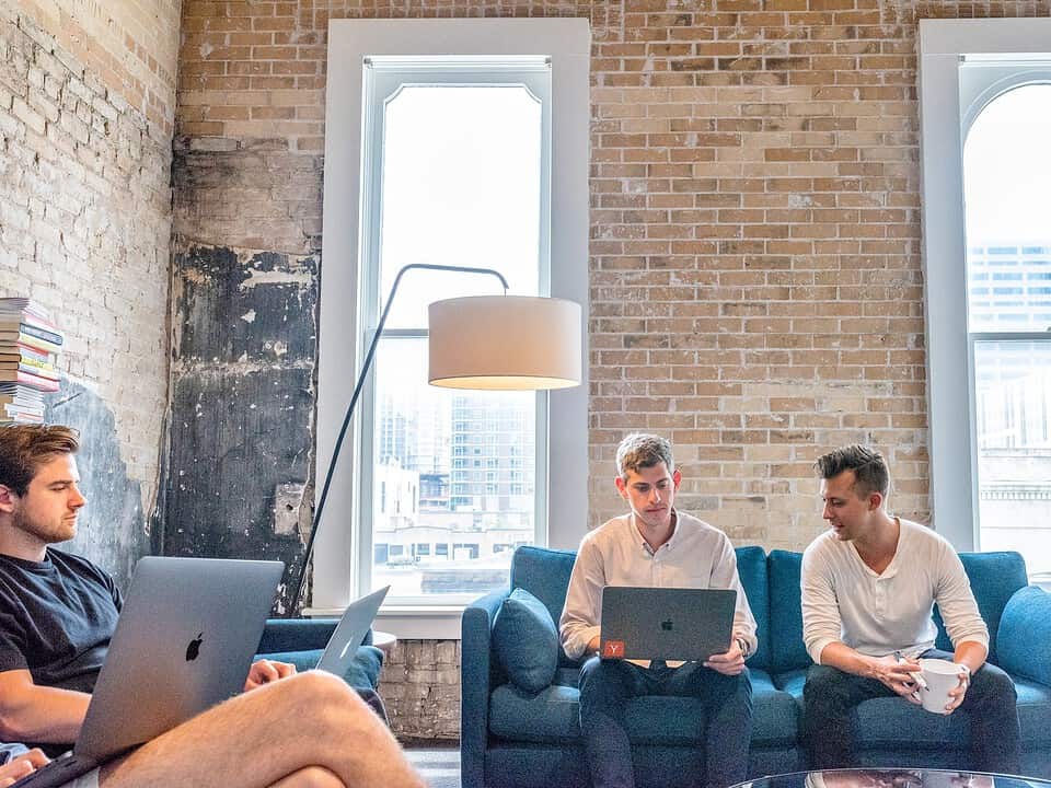 three men using macbooks in bare brick office for sales prospecting rates article