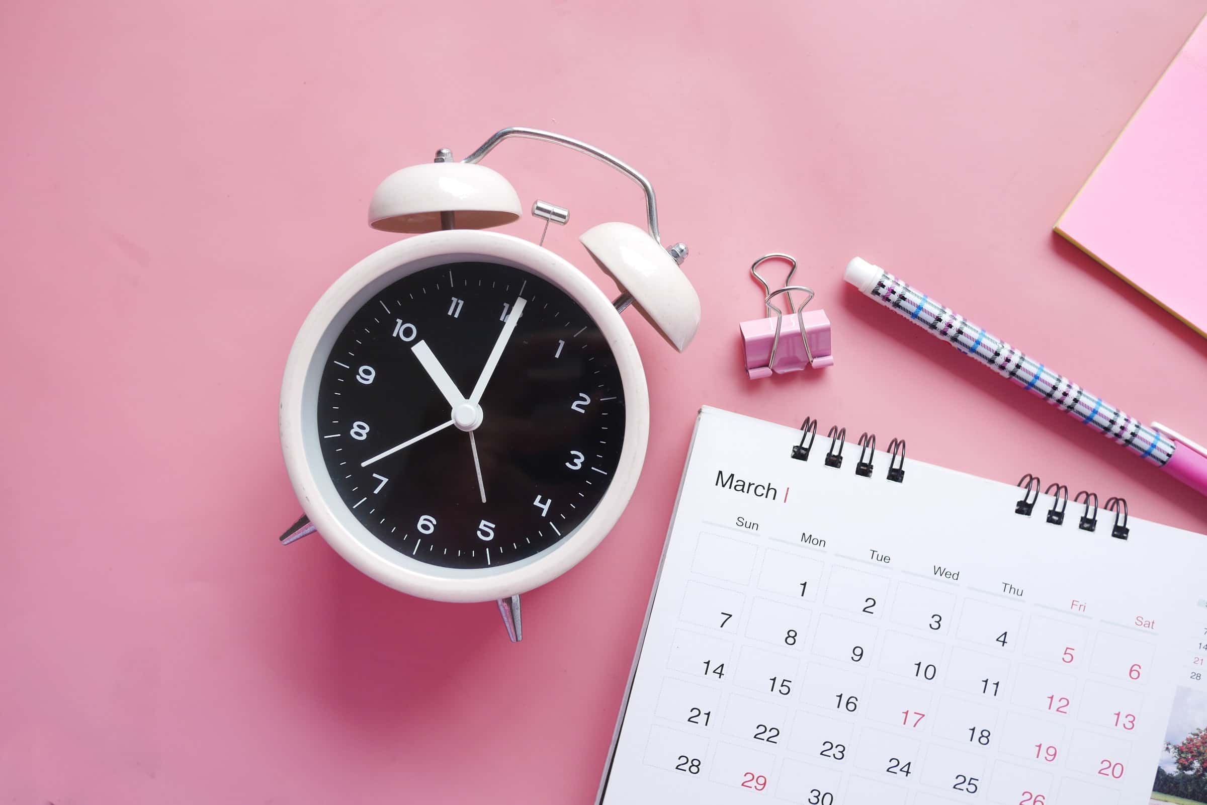 white and pink analogue alarm clock with calendar