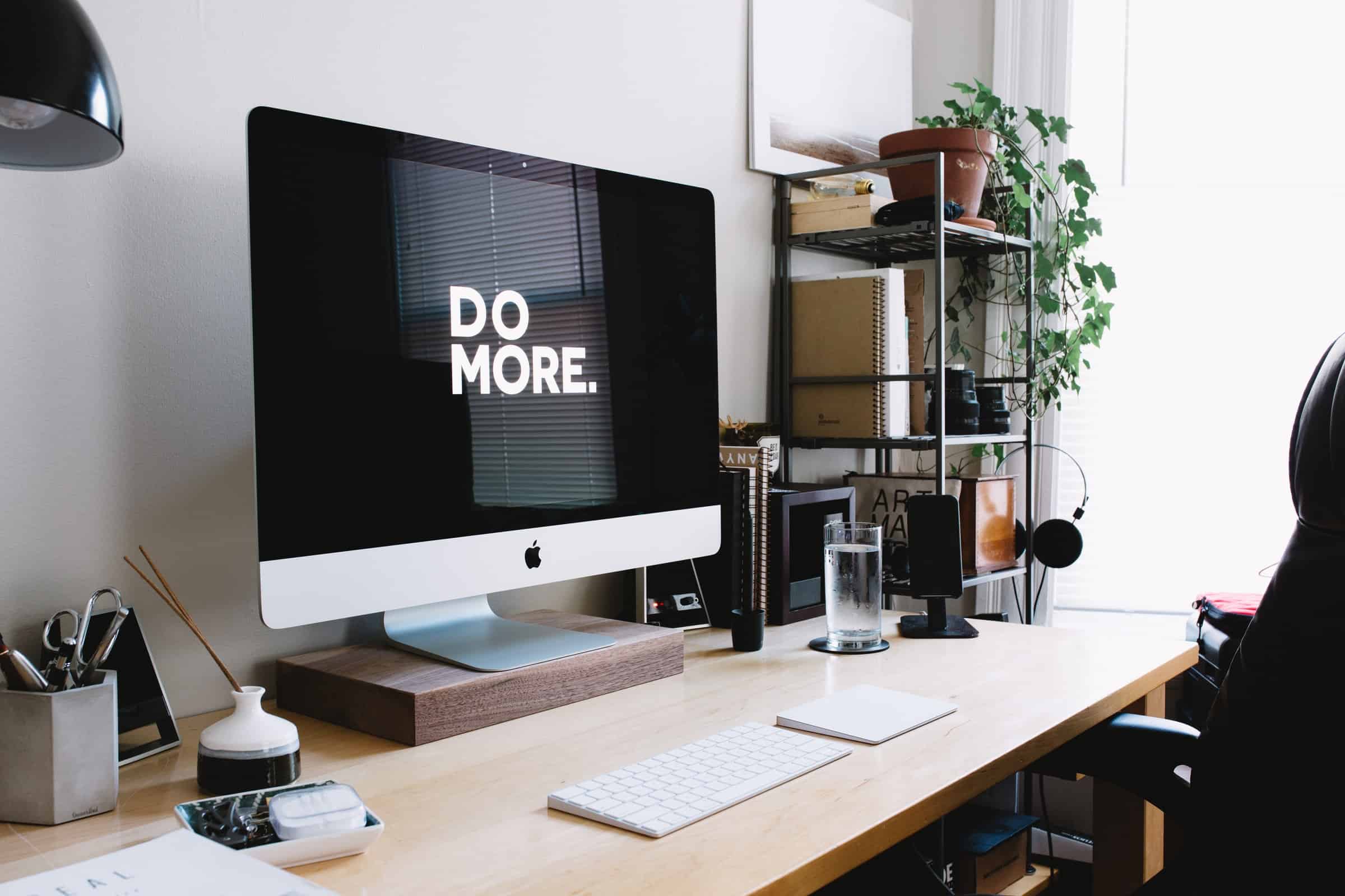 silver imac with monitor that says in white text 'do more' with silver keyboard on wooden desk for growth for business article