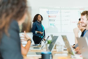 woman leading meeting with whiteboard behind her for lead generation process article