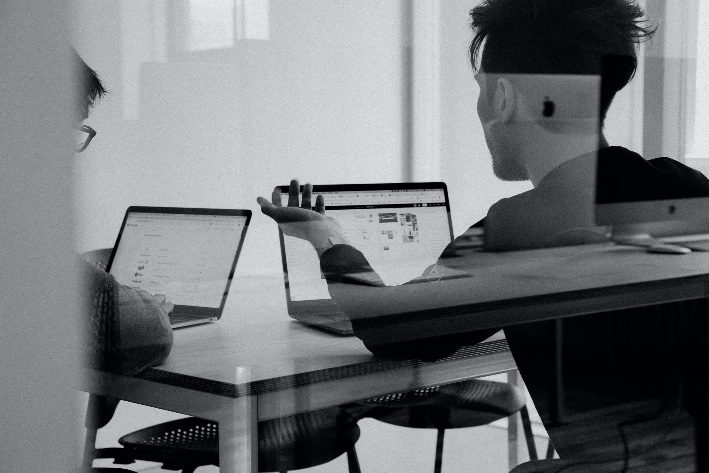 man gesturing to someone else with laptops in front of them for hubspot