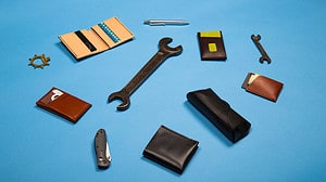 A scattered flat lay of tools and mixed leather goods on a rich blue background for crm features article