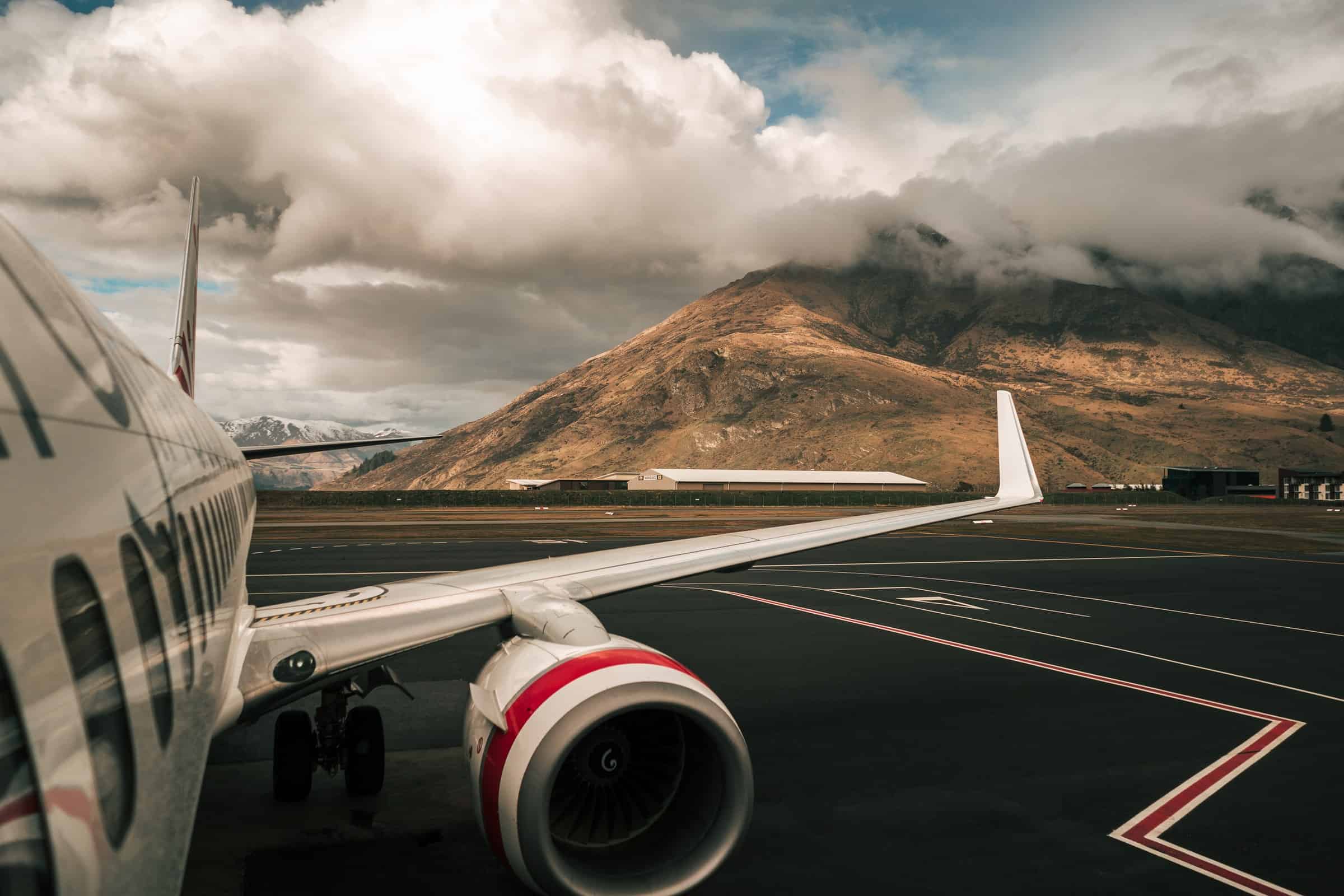 grounded plane on runway with view of mountains and clouds for crm features article