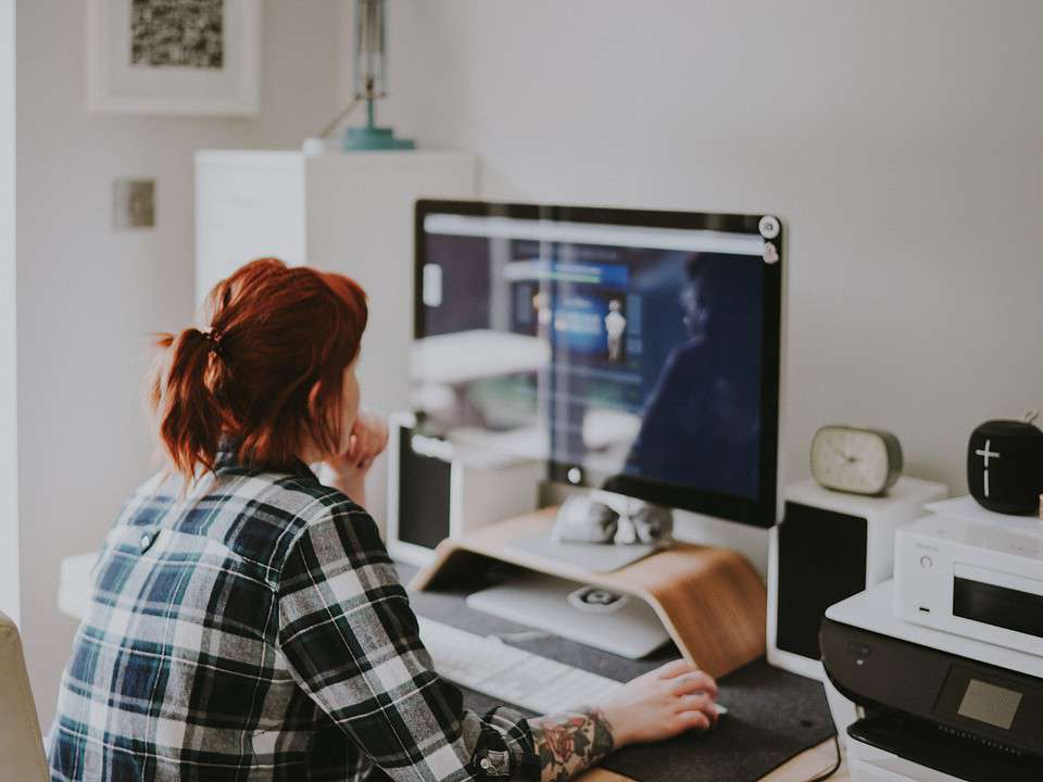 woman in a bright room sitting at a computer on the internet for what crm features article