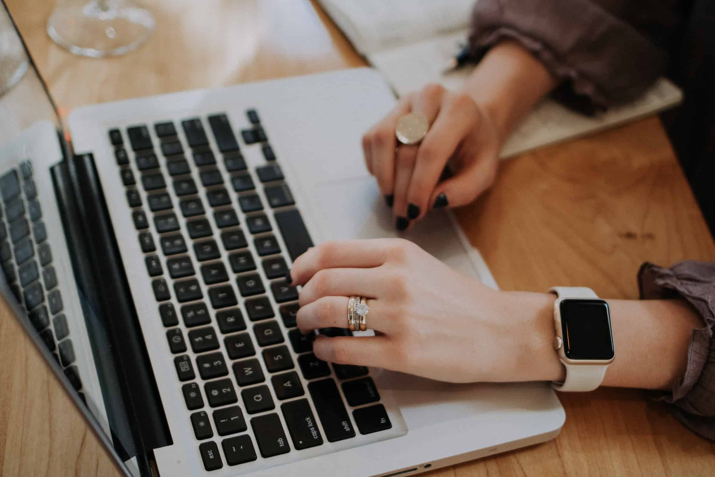 person typing on macbook on wooden desk for customer communications article