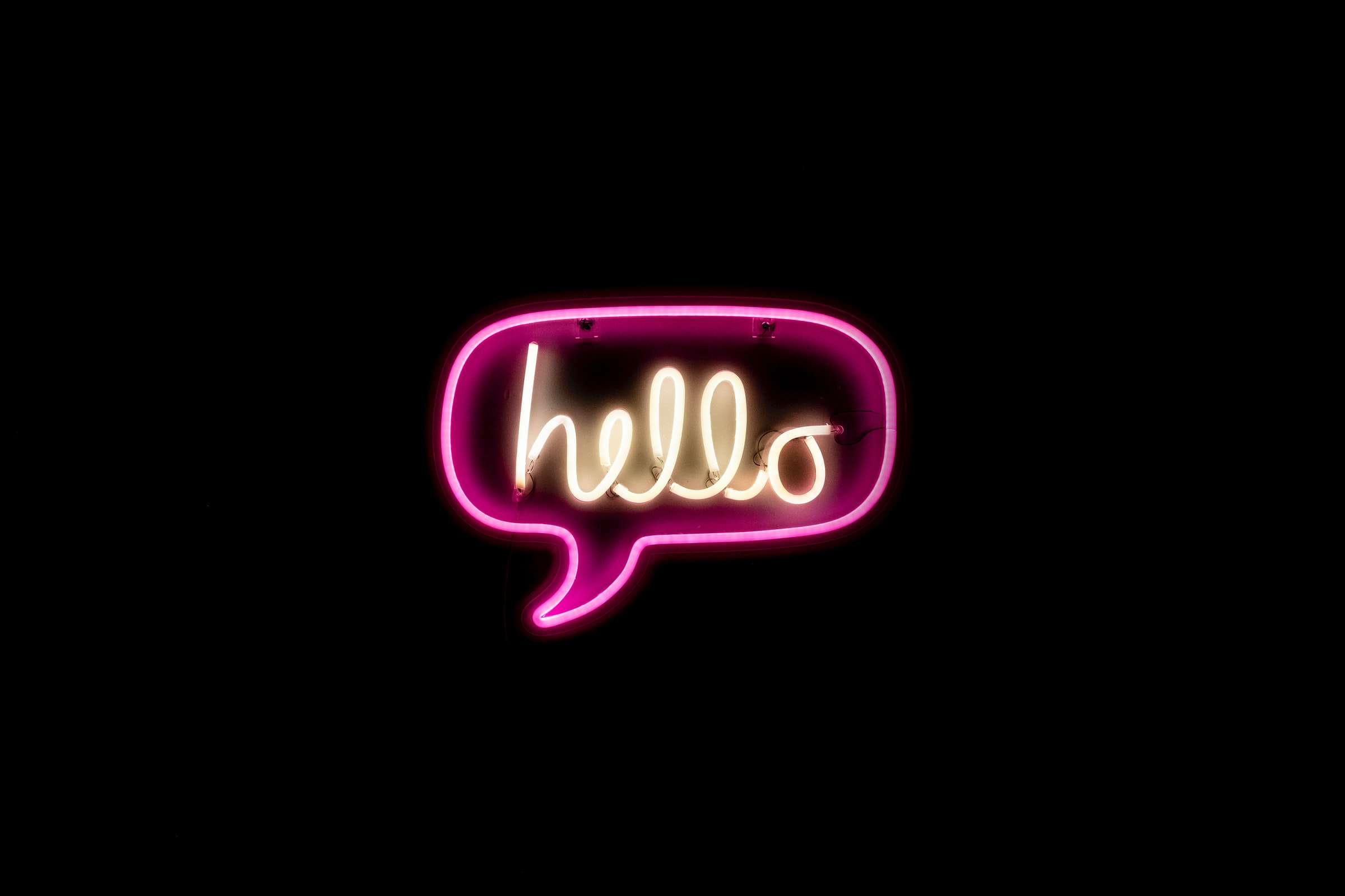 pink neon sign of a speech bubble saying 'hello' on a black background for customer communications article