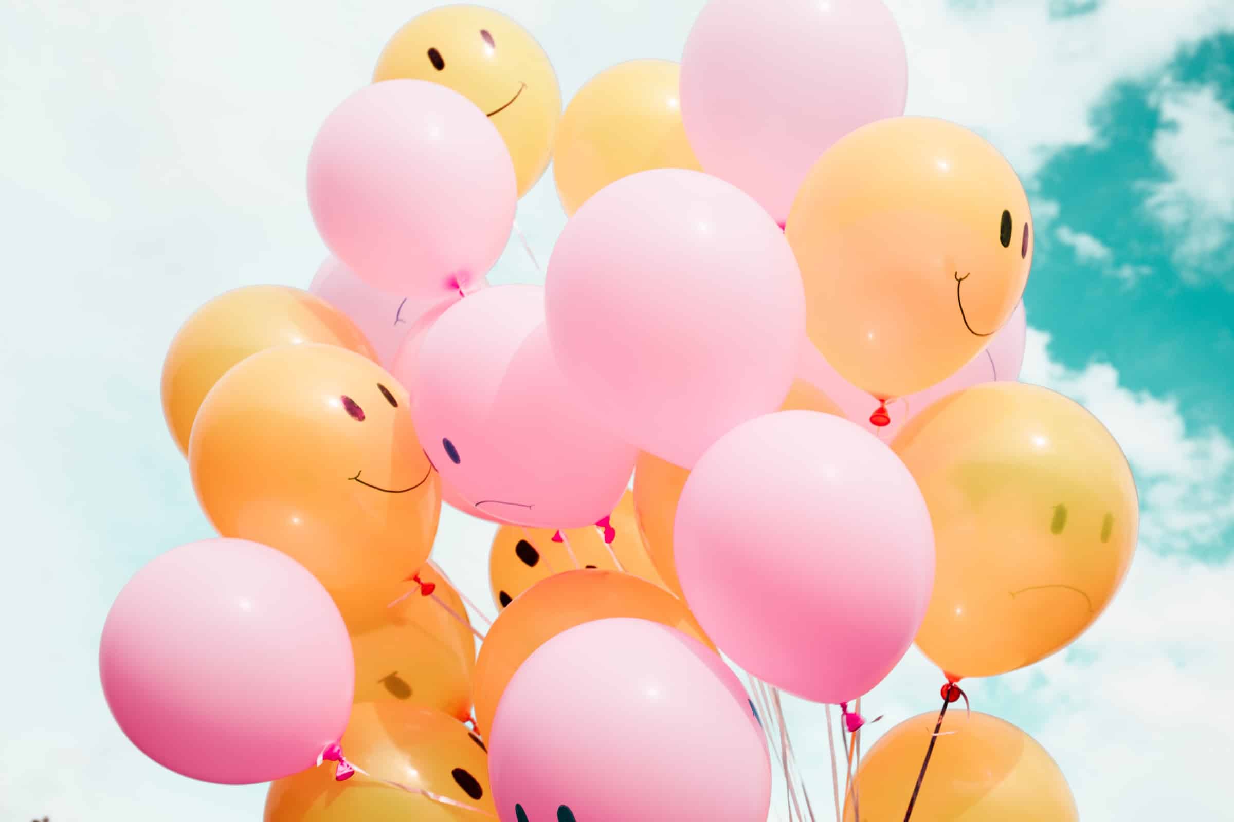 low angle photo of orange and pink balloons with printed with smiley and angry faces for buying cycle article